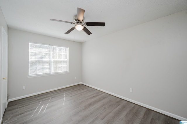 spare room featuring a ceiling fan, wood finished floors, and baseboards