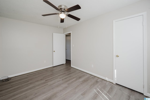 unfurnished bedroom featuring baseboards, wood finished floors, and a ceiling fan