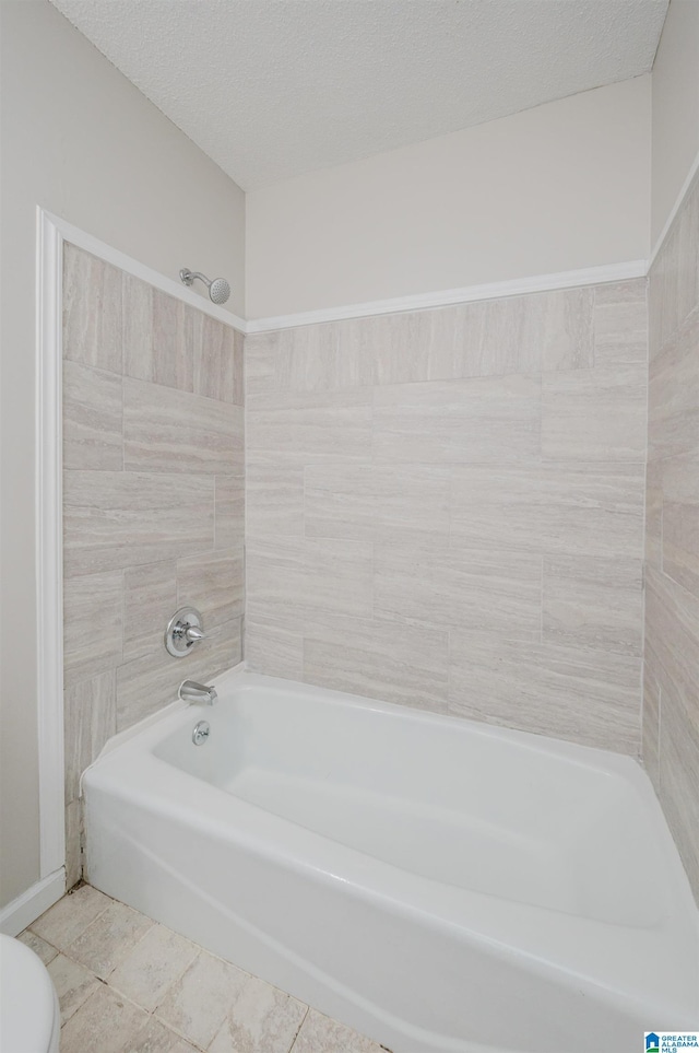 full bath with tile patterned flooring, toilet, a textured ceiling, and bathing tub / shower combination