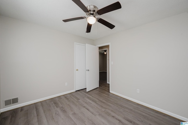 unfurnished bedroom with visible vents, a ceiling fan, baseboards, and wood finished floors