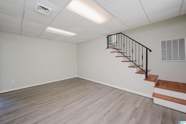 finished below grade area with wood finished floors, visible vents, and a paneled ceiling