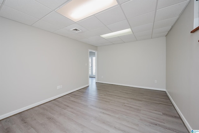 empty room with visible vents, a paneled ceiling, baseboards, and wood finished floors