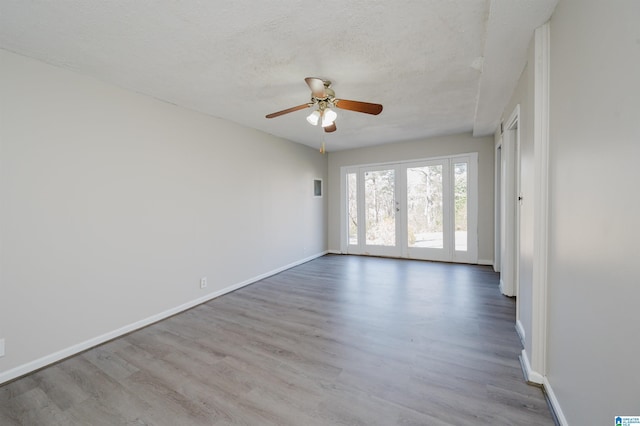 spare room featuring a textured ceiling, wood finished floors, french doors, baseboards, and ceiling fan