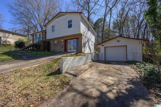 tri-level home featuring an outbuilding, stairway, concrete driveway, and a detached garage