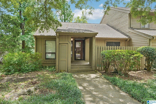 view of front of house featuring roof with shingles, board and batten siding, and fence