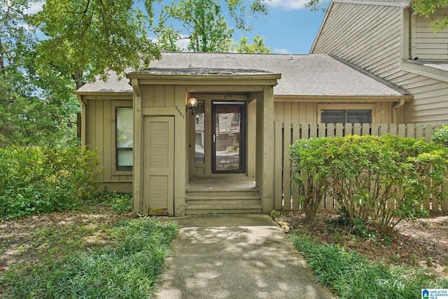 view of exterior entry with board and batten siding and roof with shingles