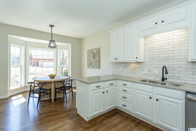 kitchen with a sink, dark wood-type flooring, dishwasher, and a peninsula