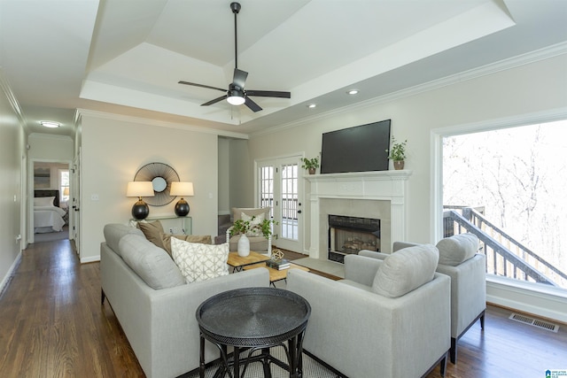 living area featuring visible vents, a raised ceiling, ceiling fan, and dark wood-style flooring