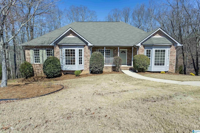 ranch-style home featuring a porch, brick siding, and a front yard