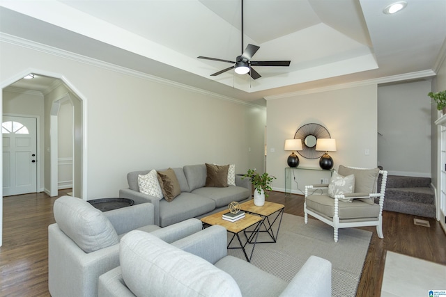 living area featuring a raised ceiling, wood finished floors, a ceiling fan, and ornamental molding