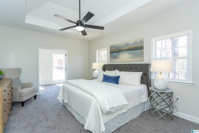 bedroom featuring a tray ceiling, baseboards, a ceiling fan, and carpet flooring