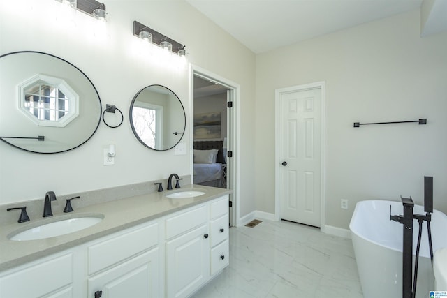 full bathroom with a soaking tub, double vanity, marble finish floor, and a sink