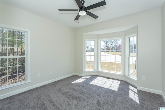 carpeted empty room with plenty of natural light, a ceiling fan, and baseboards