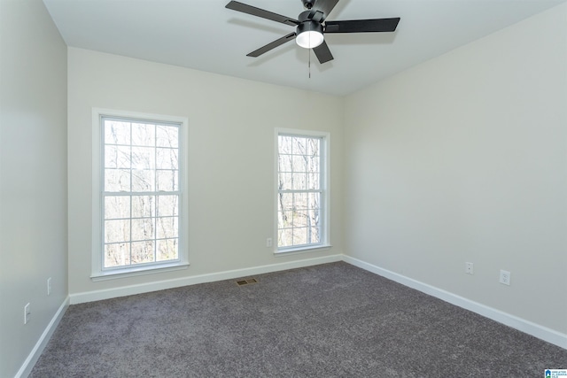 spare room with visible vents, dark carpet, a ceiling fan, and baseboards