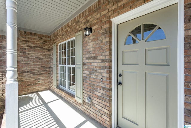 property entrance with a porch and brick siding