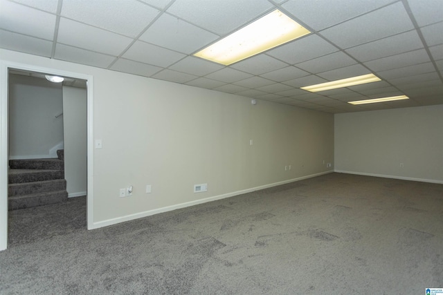 carpeted empty room with a drop ceiling, stairs, and baseboards