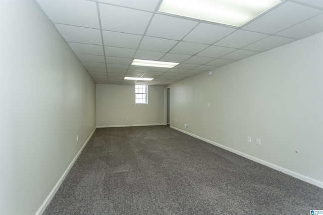 spare room with baseboards, dark colored carpet, and a drop ceiling