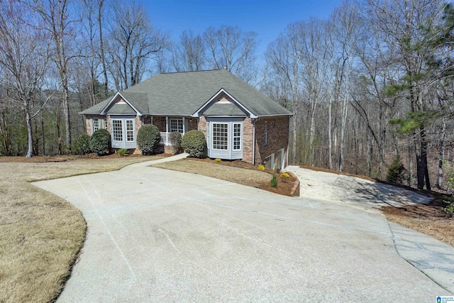 view of front of home featuring brick siding, concrete driveway, roof with shingles, a front yard, and a garage