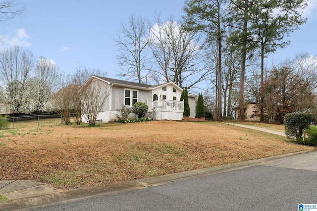 view of front facade with a deck, a front yard, and fence