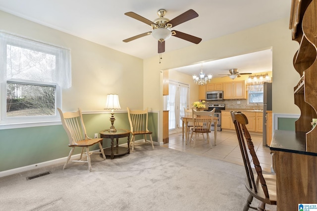 sitting room featuring visible vents, baseboards, light tile patterned flooring, ceiling fan with notable chandelier, and light colored carpet