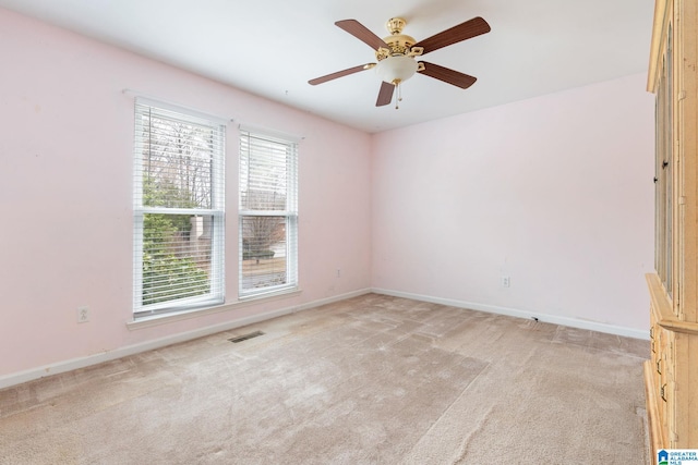 spare room featuring ceiling fan, light colored carpet, visible vents, and baseboards