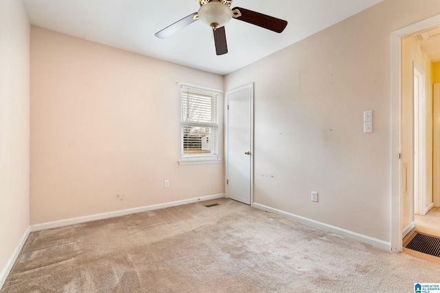 empty room with carpet flooring, baseboards, visible vents, and a ceiling fan