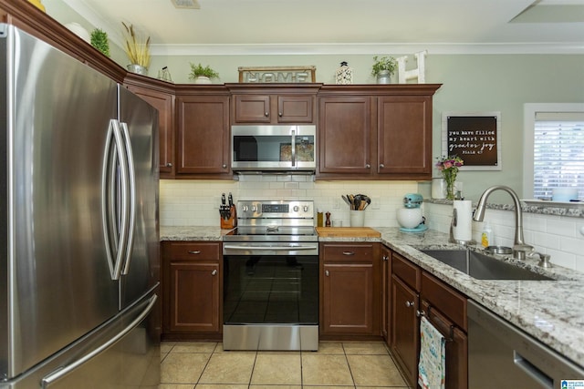 kitchen featuring decorative backsplash, ornamental molding, appliances with stainless steel finishes, and a sink