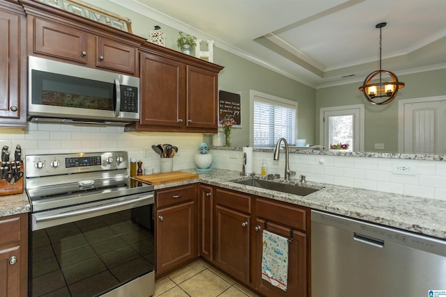 kitchen featuring backsplash, a tray ceiling, ornamental molding, stainless steel appliances, and a sink