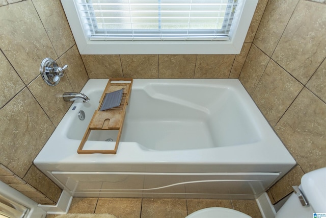 full bathroom with a wealth of natural light, toilet, and a washtub