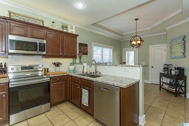 kitchen featuring a tray ceiling, a peninsula, a sink, stainless steel appliances, and backsplash