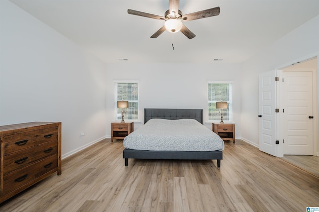 bedroom featuring visible vents, light wood-style flooring, a ceiling fan, and baseboards