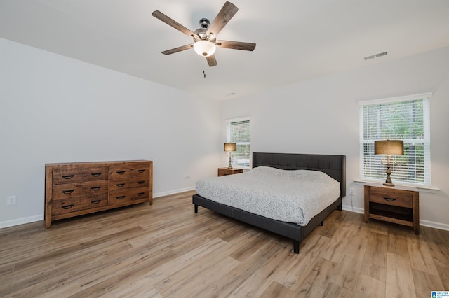 bedroom featuring visible vents, multiple windows, and light wood-style floors