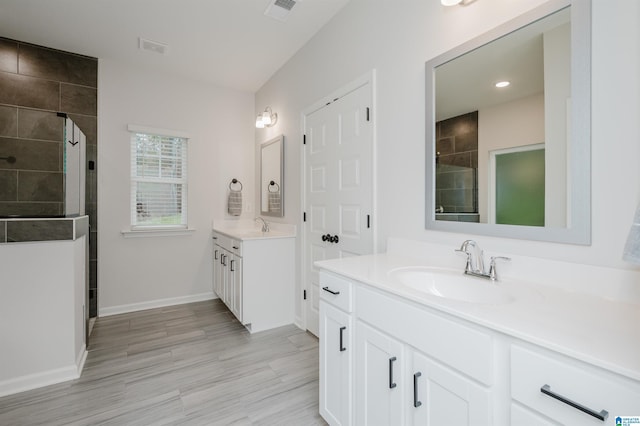 bathroom with baseboards, visible vents, two vanities, a sink, and a shower stall