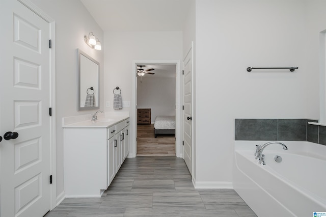 ensuite bathroom featuring baseboards, a garden tub, ensuite bath, and vanity