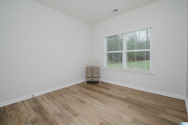 unfurnished room with wood finished floors, visible vents, and baseboards