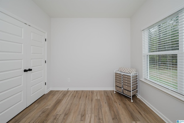 unfurnished bedroom with a closet, baseboards, and light wood finished floors