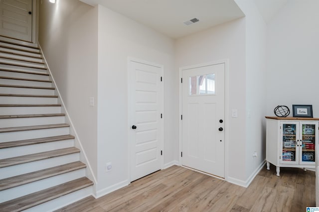 foyer with stairs, light wood-style flooring, baseboards, and visible vents