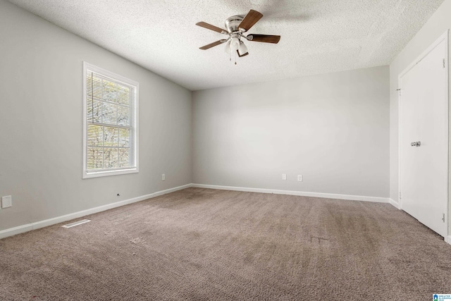 carpeted spare room with visible vents, baseboards, a textured ceiling, and a ceiling fan