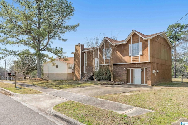 view of front of home with brick siding, concrete driveway, a front yard, and fence