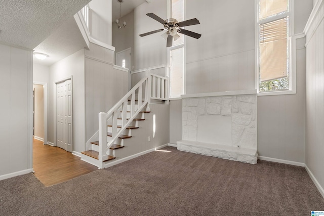 staircase with carpet floors, a textured ceiling, a towering ceiling, and a fireplace