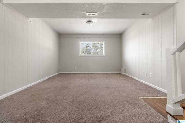 carpeted empty room with visible vents, baseboards, and a textured ceiling