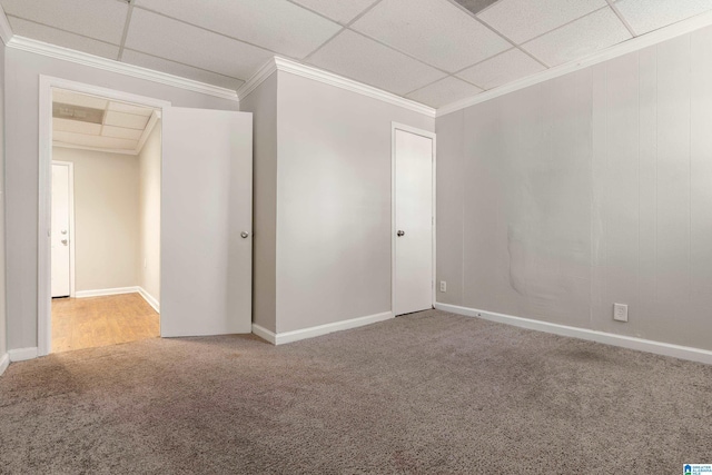 carpeted empty room featuring crown molding, a paneled ceiling, and baseboards