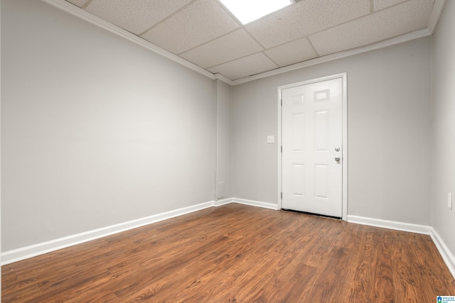 spare room featuring dark wood-style floors, a drop ceiling, baseboards, and ornamental molding