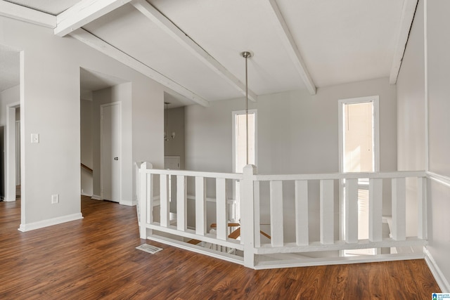 hall featuring wood finished floors, visible vents, baseboards, beamed ceiling, and an upstairs landing