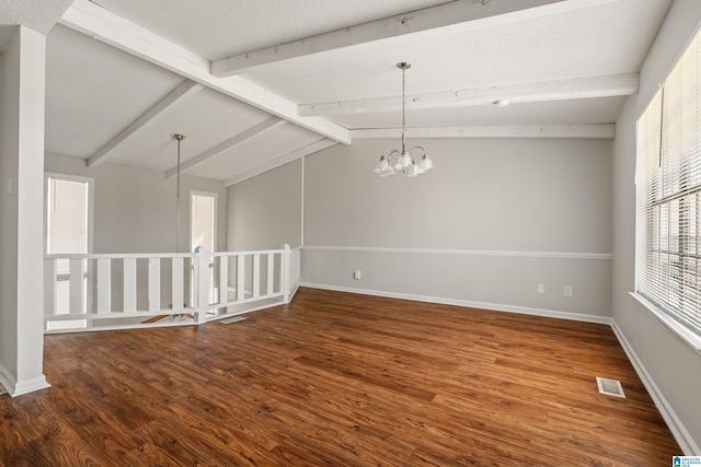 empty room featuring wood finished floors, visible vents, baseboards, an inviting chandelier, and vaulted ceiling with beams