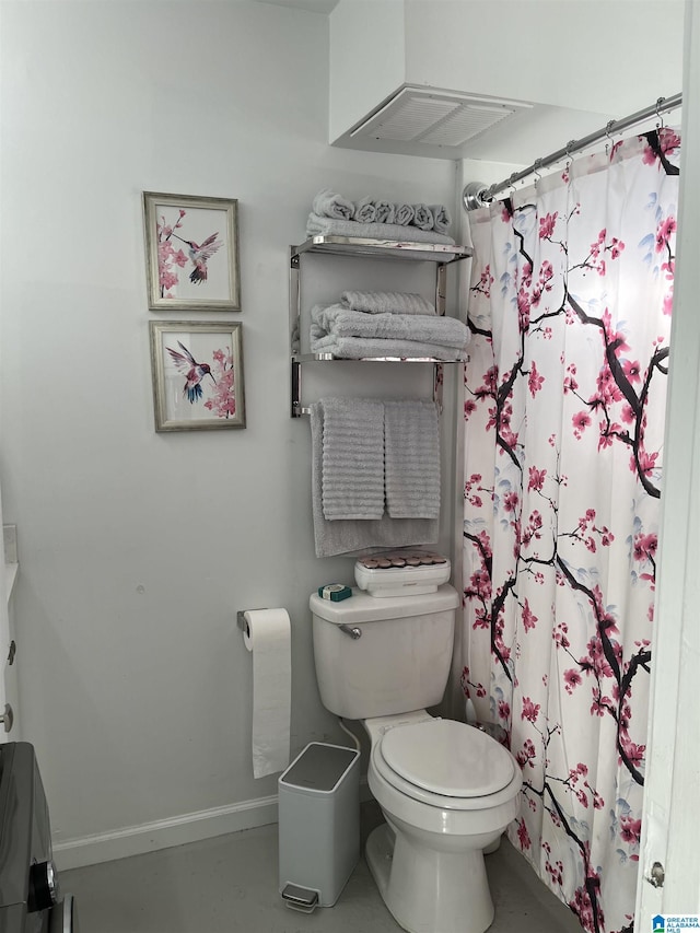 full bath featuring curtained shower, toilet, and baseboards