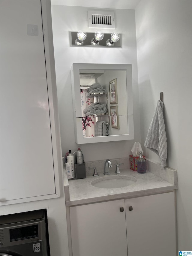 bathroom featuring visible vents, washer / dryer, and vanity