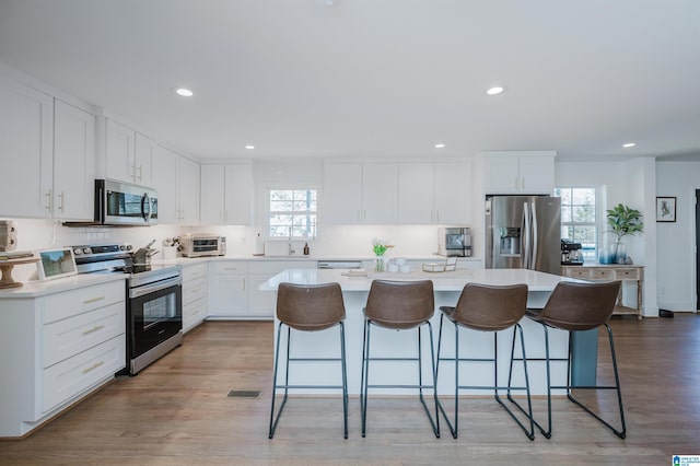 kitchen featuring a wealth of natural light, a kitchen breakfast bar, a kitchen island, and appliances with stainless steel finishes