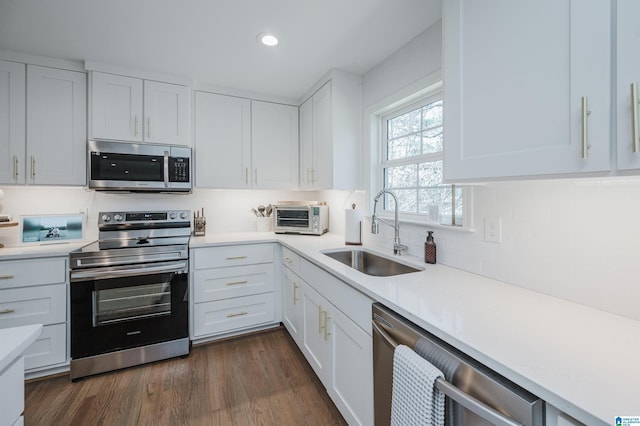 kitchen featuring appliances with stainless steel finishes, white cabinetry, light countertops, and a sink