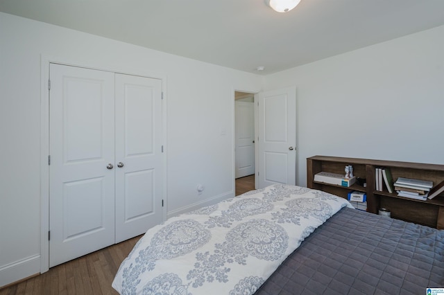 bedroom featuring dark wood finished floors, baseboards, and a closet